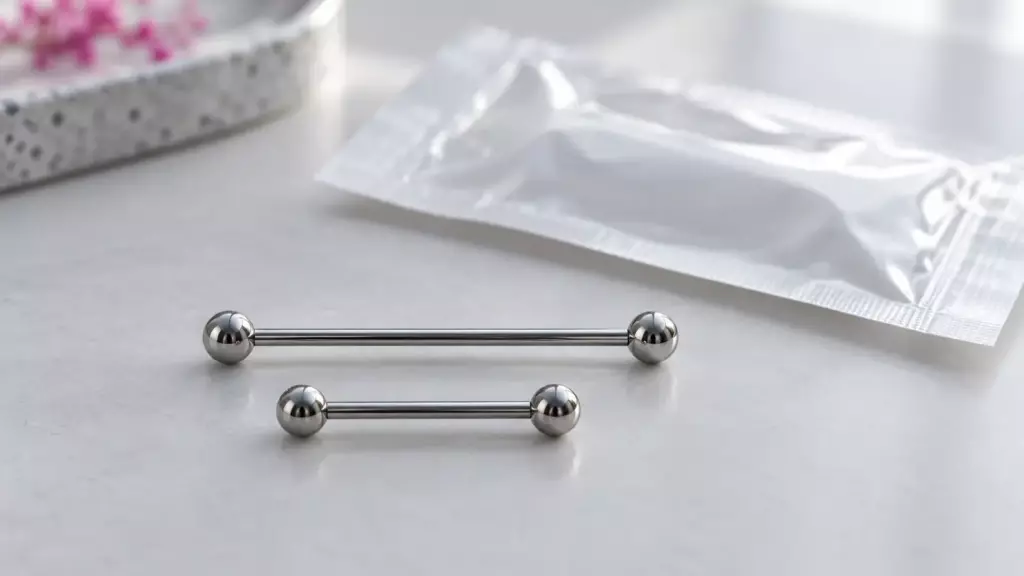 Zwei Titan-Piercingstäbe in lang und kurz neben einer Sterilverpackung (Symbolbild)